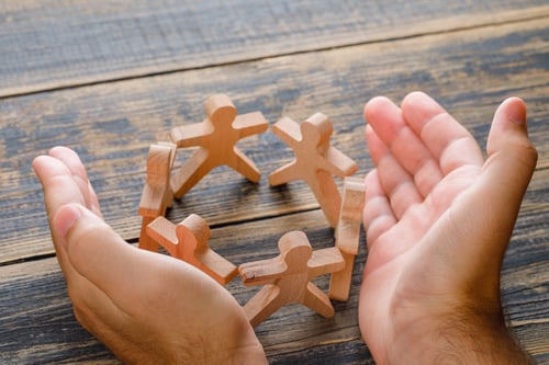 business-success-concept-on-wooden-table-top-view-hands-protecting-wooden-figures-of-people